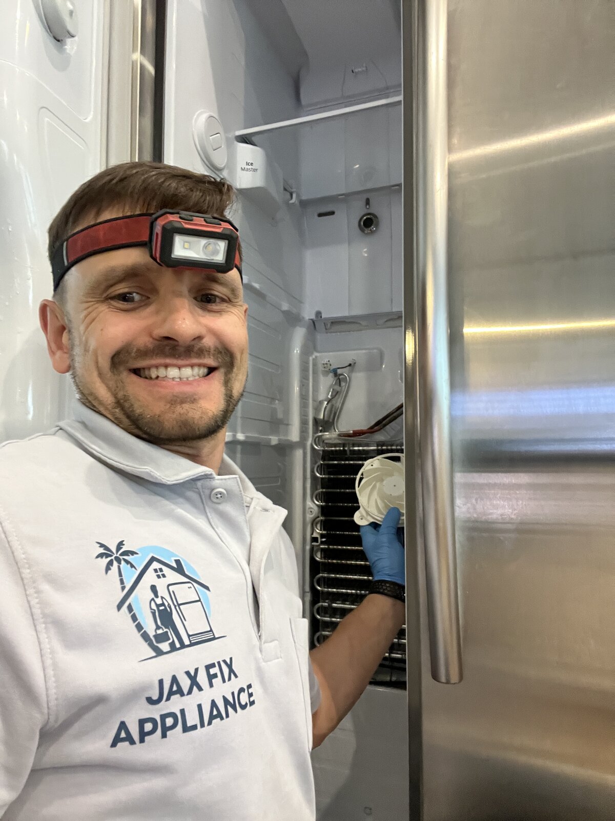 Konstantin in branded Jax Fix Appliance polo servicing freezer evaporator coils and ice maker