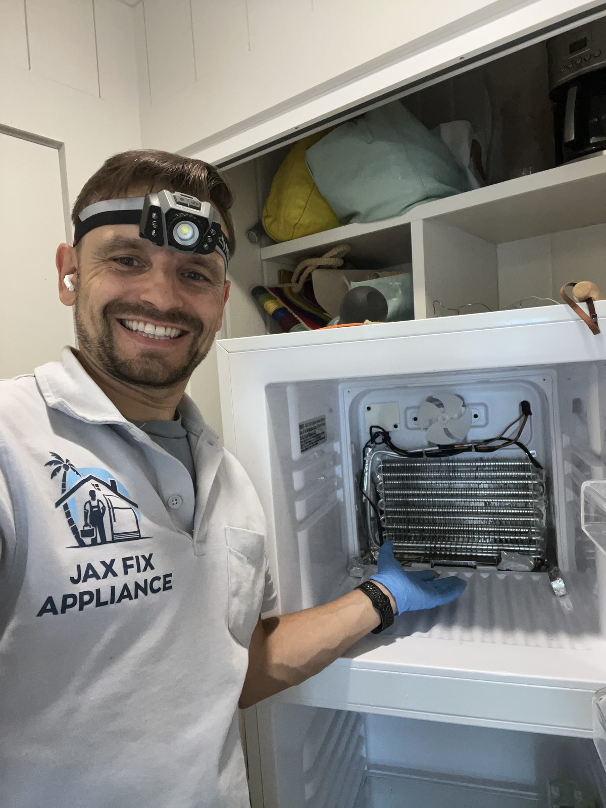 Konstantin at an upright freezer with the evaporator coil exposed during a no-freeze repair